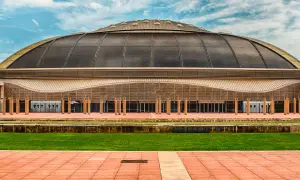 Palau Sant Jordi, z charakterystyczną kopułą, prezentuje się imponująco na tle błękitnego nieba z chmurami.