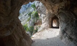 Kamieniste szlaki Picos de Europa wiodą przez skalne tunele, odsłaniając zapierające dech w piersiach widoki na góry i zieleń.
