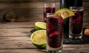 Orzeźwiający hiszpański napój alkoholowy, sangria, podana z lodem i plasterkami limonki na drewnianym stole.