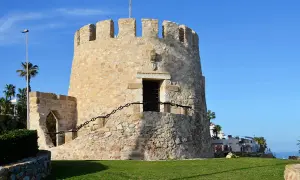 Kamienna wieża strażnicza, jedna z atrakcji Torrevieja, z widokiem na morze i palmy.