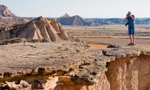 Mężczyzna robi zdjęcie na krawędzi klifu w Bardenas Reales, podziwiając surowy, pustynny krajobraz.