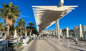Spacerem po malaga park, pod palmami i nowoczesną pergolą, ludzie odpoczywają w kawiarniach i spacerują.