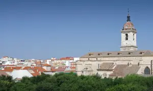 Widok na miasto Ciudad Real z kościołem i jego wieżą zegarową na tle błękitnego nieba.
