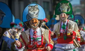 Ludzie w maskach i barwnych strojach, święta w Hiszpanii. Widać malunek wilka na kapeluszu.
