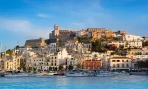 Widok na port z żaglówkami i wzgórzem z białymi domami i katedrą. Ibiza atrakcje zachwycają!