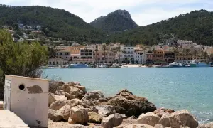 Malowniczy port d'Andratx z kolorowymi budynkami, łodziami i górami w tle.