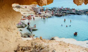 Ludzie kąpią się i opalają na skalistej plaży. Idealna pogoda, jak na hiszpania temperatura roczna.