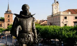 Pomnik Cervantesa w Alcalá de Henares, z ratuszem i wieżą zegarową w tle.