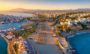 Złociste słońce oświetla port i pustą plażę w Nerja. Długi deptak z rzędami parasoli prowadzi do turkusowego morza.