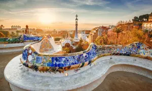 Kolorowa mozaika zdobi ławkę w Parku Güell, dziele Gaudiego. W tle widać panoramę Barcelony o zachodzie słońca.