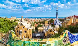 Kolorowe budowle Antonio Gaudiego w Parku Güell, Barcelona, z widokiem na miasto i morze.