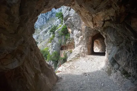 Kamieniste szlaki Picos de Europa wiodą przez skalne tunele, odsłaniając zapierające dech w piersiach widoki na góry i zieleń.