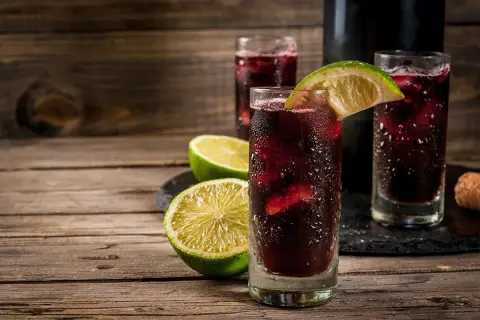 Orzeźwiający hiszpański napój alkoholowy, sangria, podana z lodem i plasterkami limonki na drewnianym stole.