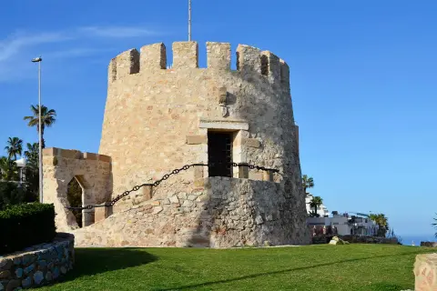 Kamienna wieża strażnicza, jedna z atrakcji Torrevieja, z widokiem na morze i palmy.