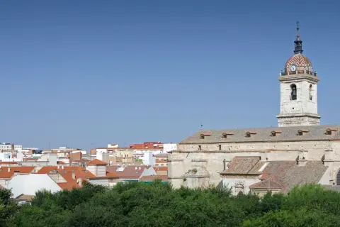 Widok na miasto Ciudad Real z kościołem i jego wieżą zegarową na tle błękitnego nieba.