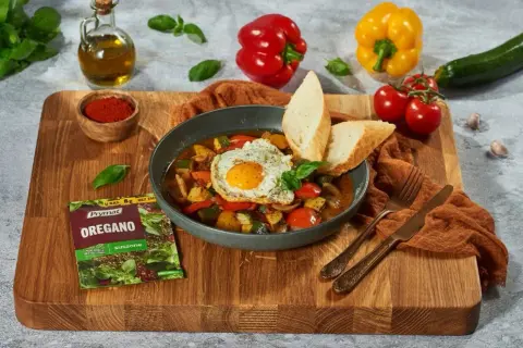 Pyszne pisto manchego z jajkiem sadzonym i pieczywem, doprawione oregano.