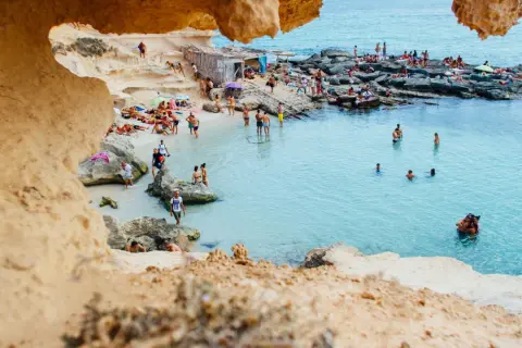 Ludzie kąpią się i opalają na skalistej plaży. Idealna pogoda, jak na hiszpania temperatura roczna.