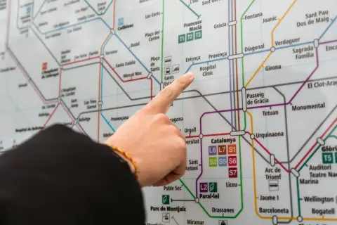 Palec na mapie metra w Barcelonie, wskazujący stację Hospital Clínic. Planujesz podróż z lotniska Barcelona?