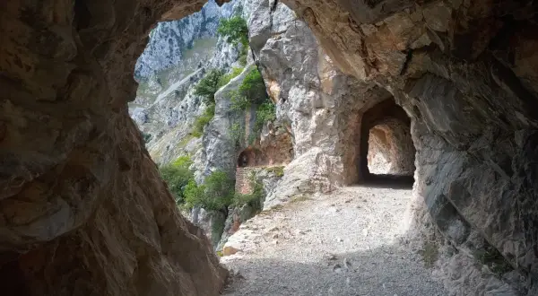 Kamieniste szlaki Picos de Europa wiodą przez skalne tunele, odsłaniając zapierające dech w piersiach widoki na góry i zieleń.