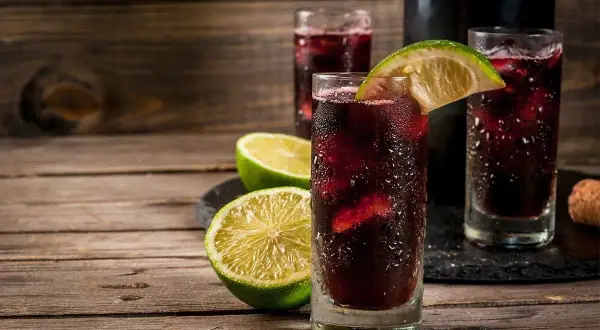 Orzeźwiający hiszpański napój alkoholowy, sangria, podana z lodem i plasterkami limonki na drewnianym stole.