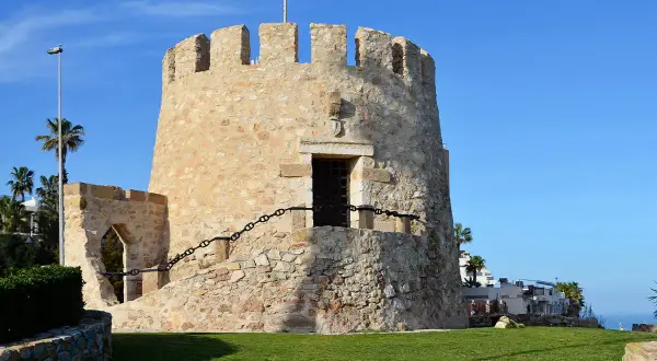 Kamienna wieża strażnicza, jedna z atrakcji Torrevieja, z widokiem na morze i palmy.