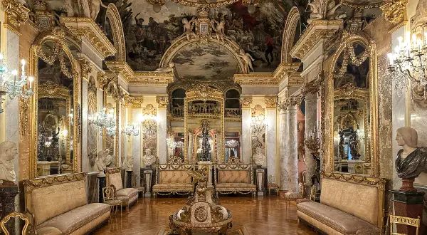 Złocone wnętrze pałacowe, przypominające salę w madryckich muzeach, z malowidłami na suficie i bogatymi meblami.