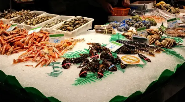 Świeże owoce morza na lodzie w La Boqueria: krewetki, homary, kraby i małże.