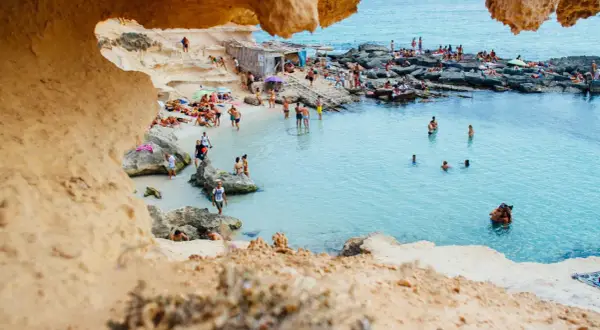 Ludzie kąpią się i opalają na skalistej plaży. Idealna pogoda, jak na hiszpania temperatura roczna.