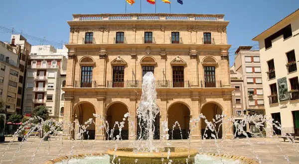 Fontanna na placu przed ratuszem w Castellón de la Plana, Walencja. Flagi Hiszpanii i regionu Walencji powiewają na dachu.