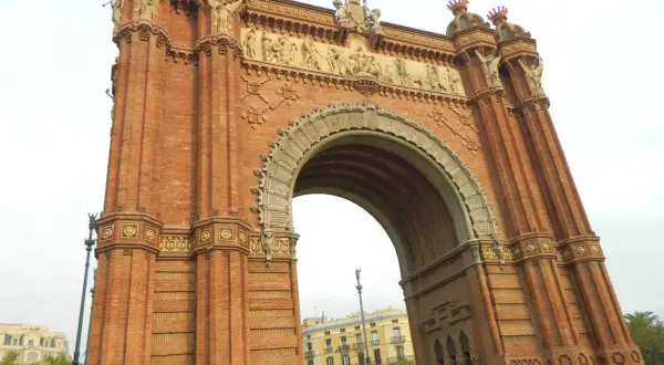 Majestatyczny łuk triumfalny Barcelona, zbudowany z cegły, z bogatymi zdobieniami i rzeźbami.