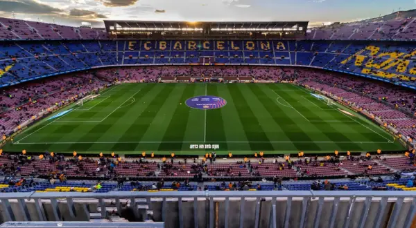 Widok na pusty stadion FC Barcelona, Camp Nou, z rzędem siedzeń w kolorach klubu i zieloną murawą.