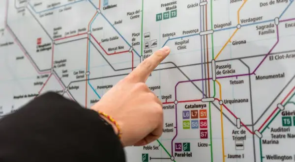 Palec na mapie metra w Barcelonie, wskazujący stację Hospital Clínic. Planujesz podróż z lotniska Barcelona?
