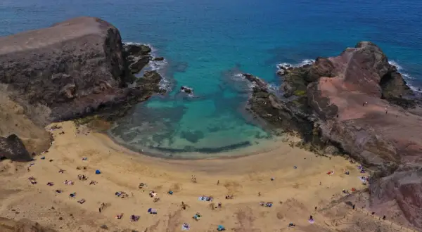 Zatoka Papagayo na Lanzarote, z turkusową wodą i piaszczystą plażą, gdzie odpoczywają turyści.