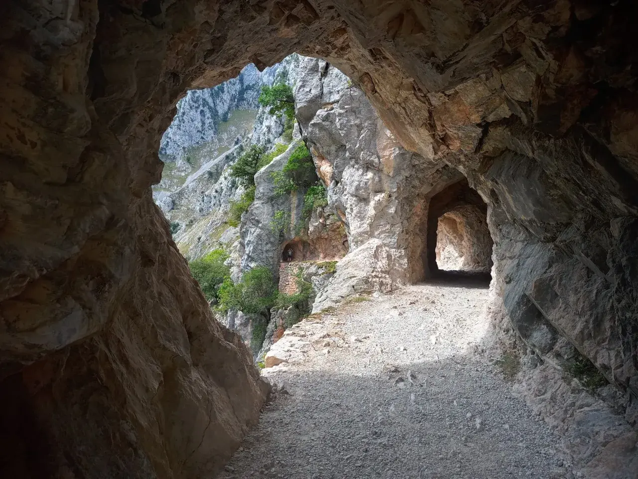 Kamieniste szlaki Picos de Europa wiodą przez skalne tunele, odsłaniając zapierające dech w piersiach widoki na góry i zieleń.