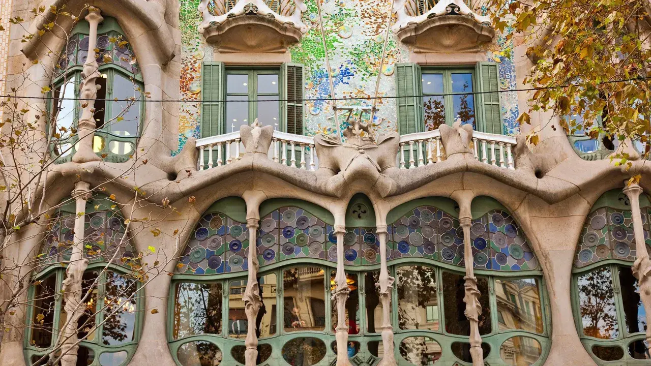 Fasada Casa Batlló w Barcelonie, z falującymi formami, mozaikami i kolorowymi witrażami, jakby wyjęta z baśni.