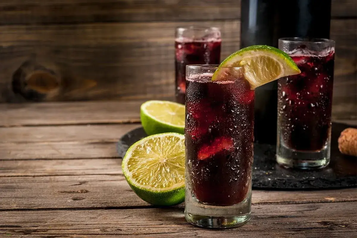 Orzeźwiający hiszpański napój alkoholowy, sangria, podana z lodem i plasterkami limonki na drewnianym stole.