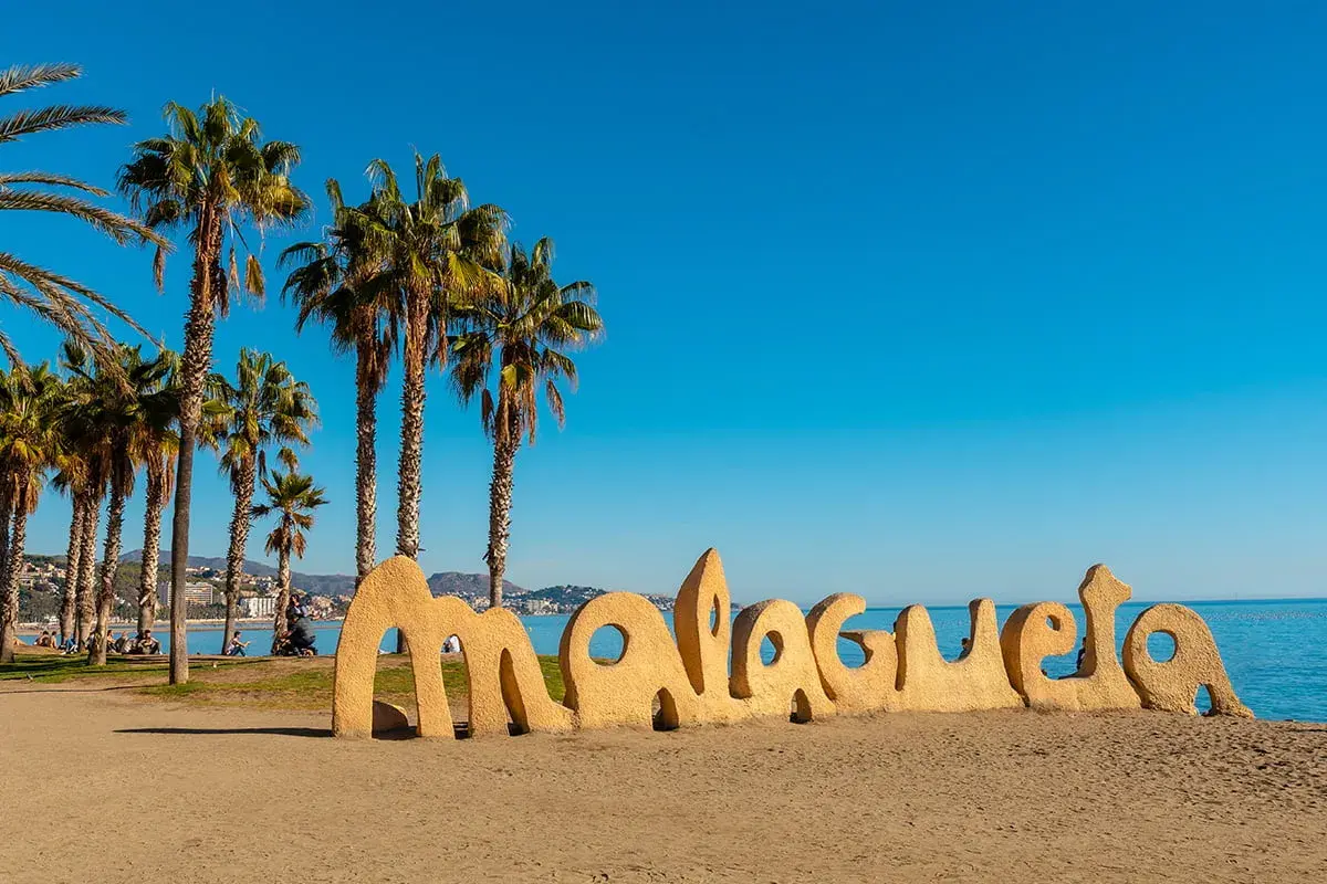Słoneczne andaluzja plaże z palmami i napisem "Malagueta". Idealne miejsce na relaks.