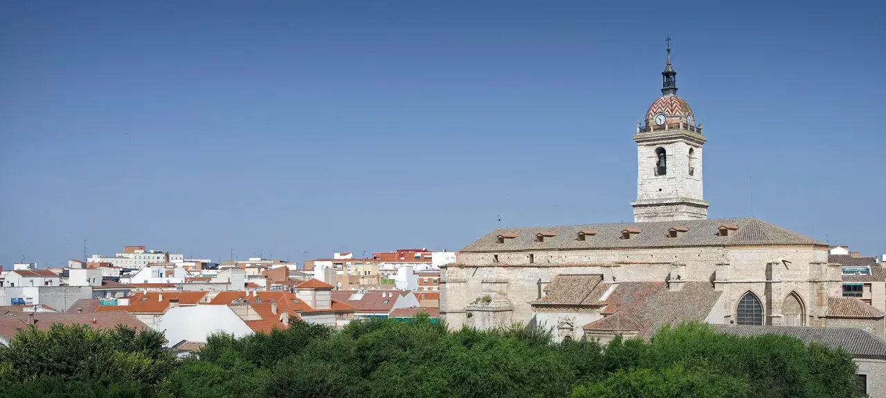 Widok na miasto Ciudad Real z kościołem i jego wieżą zegarową na tle błękitnego nieba.