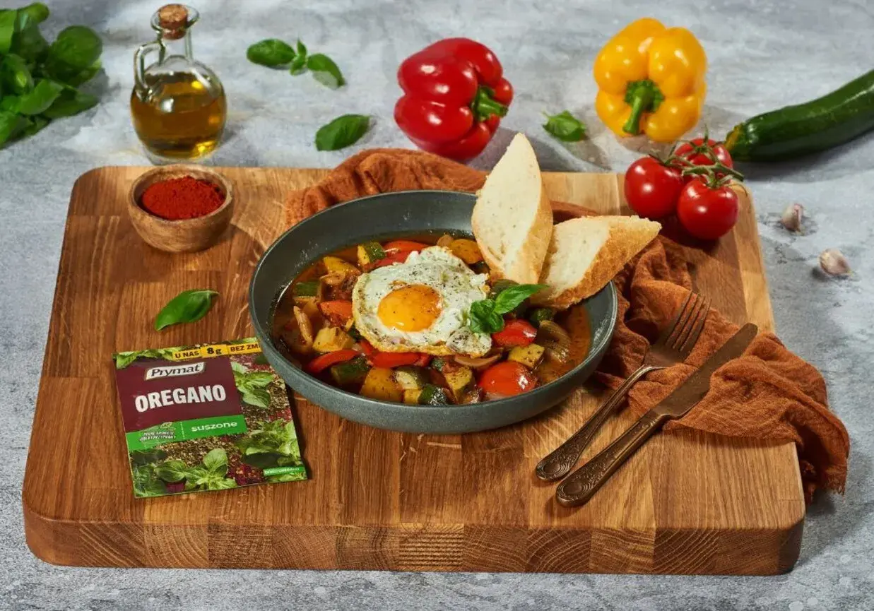 Pyszne pisto manchego z jajkiem sadzonym i pieczywem, doprawione oregano.