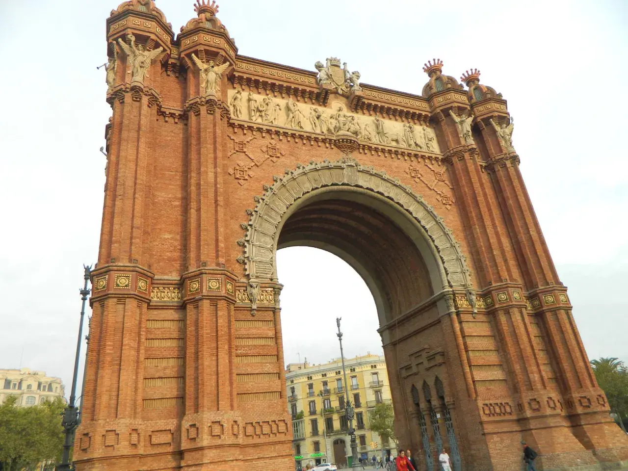 Majestatyczny łuk triumfalny Barcelona, zbudowany z cegły, z bogatymi zdobieniami i rzeźbami.