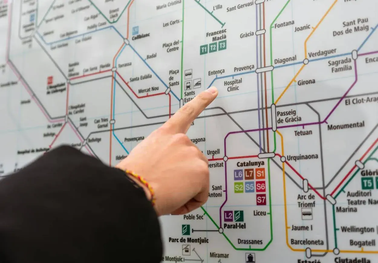 Palec na mapie metra w Barcelonie, wskazujący stację Hospital Clínic. Planujesz podróż z lotniska Barcelona?