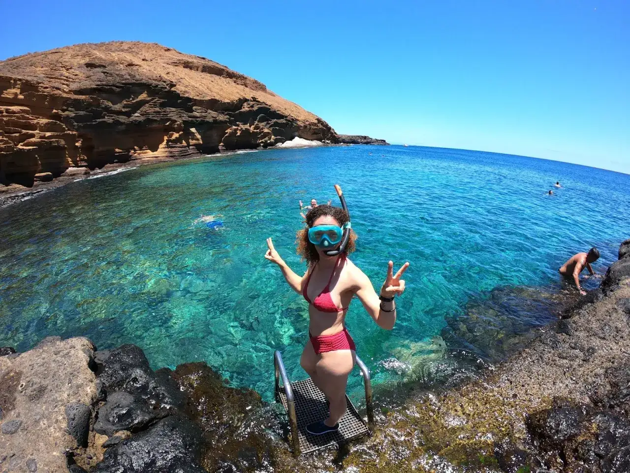 Wyspy Kanaryjskie pogoda grudzień: dziewczyna w masce do snorkelingu cieszy się słońcem i krystalicznie czystą wodą.