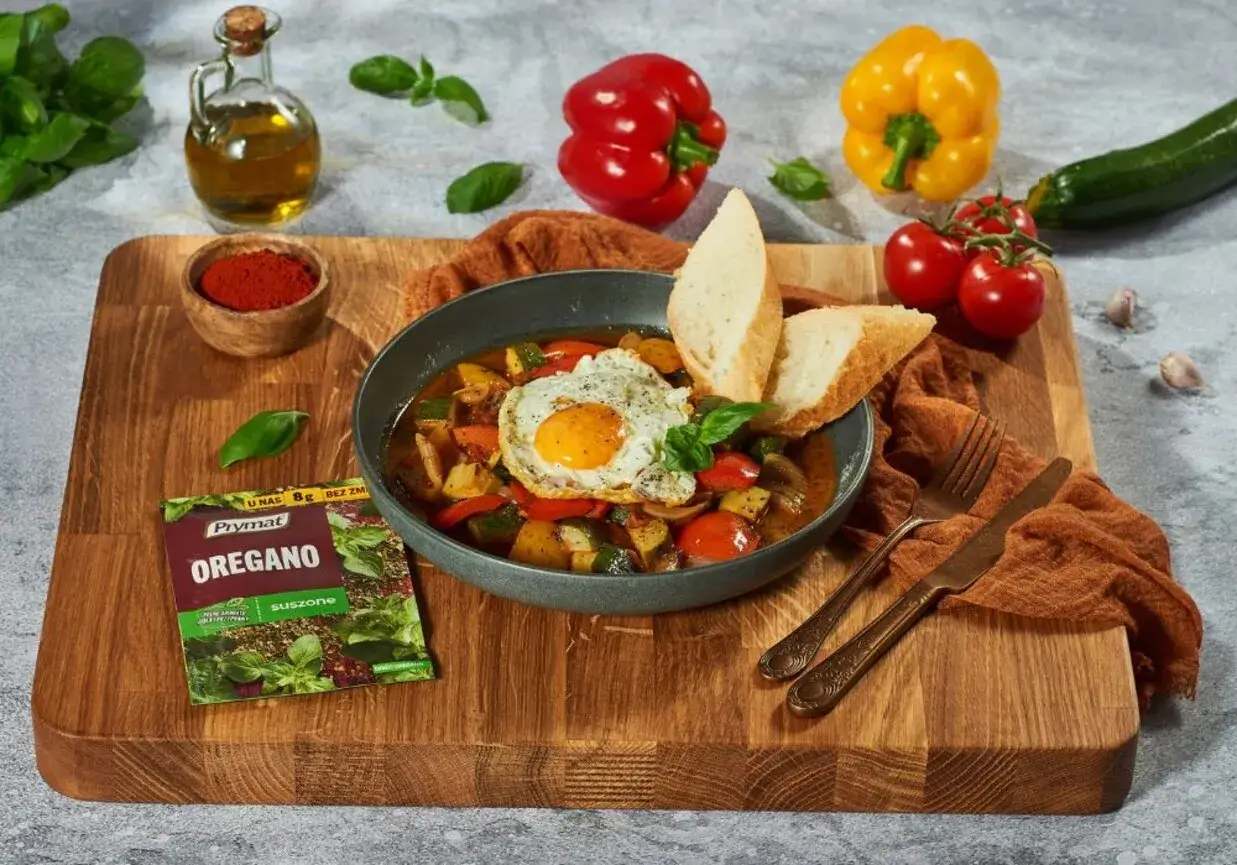 Pisto manchego z jajkiem sadzonym i pieczywem, doprawione oregano.