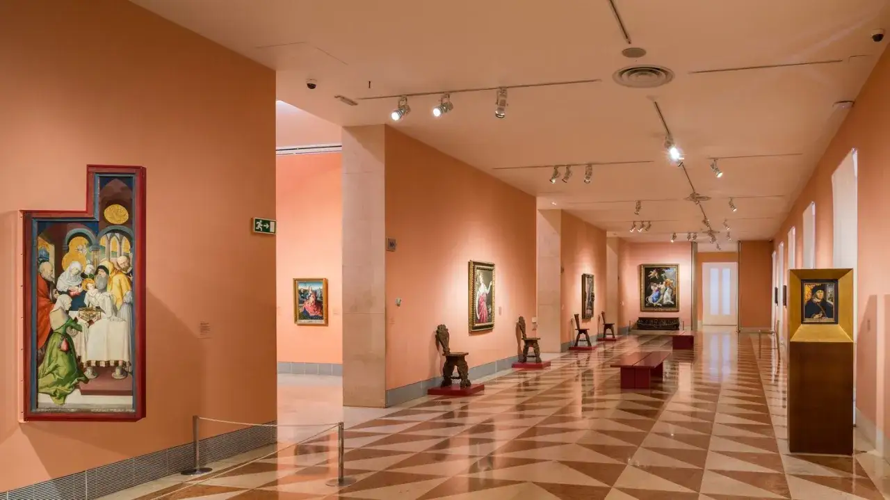 Korytarz w muzeum Thyssen-Bornemisza z obrazami i rzeźbami.