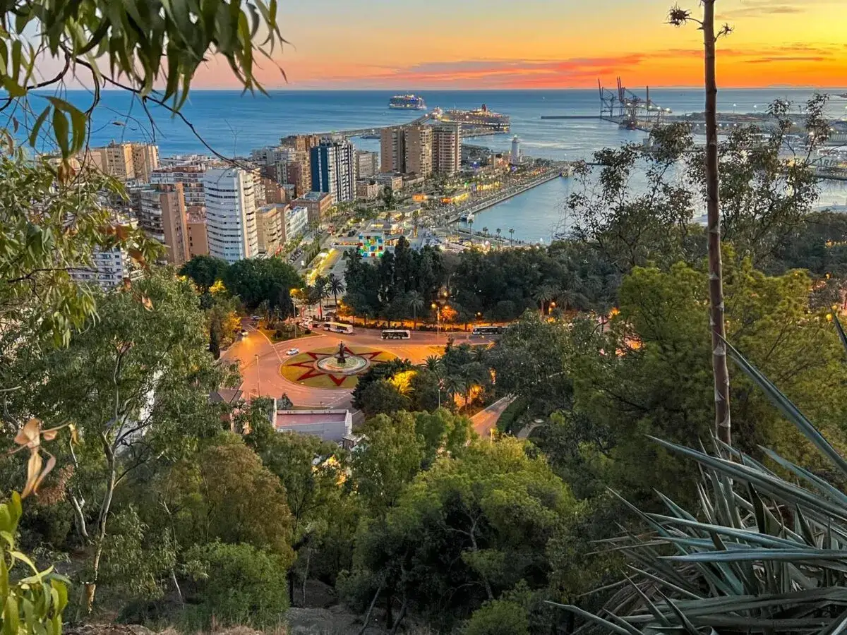 Zachód słońca nad Malagą. Widok na miasto, port z statkami i latarnią morską. Wspaniałe malaga atrakcje.
