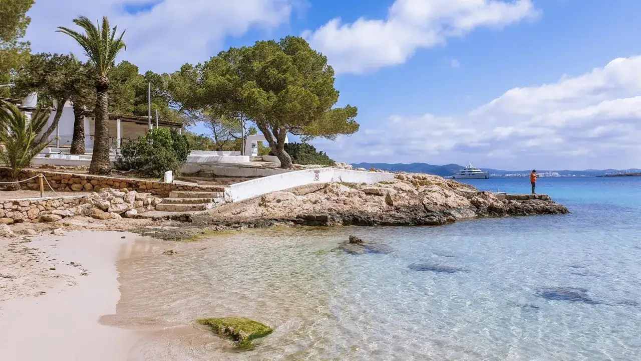 Piękna plaża z palmami, krystalicznie czysta woda i luksusowy jacht na horyzoncie. To idealne ibiza atrakcje dla każdego.