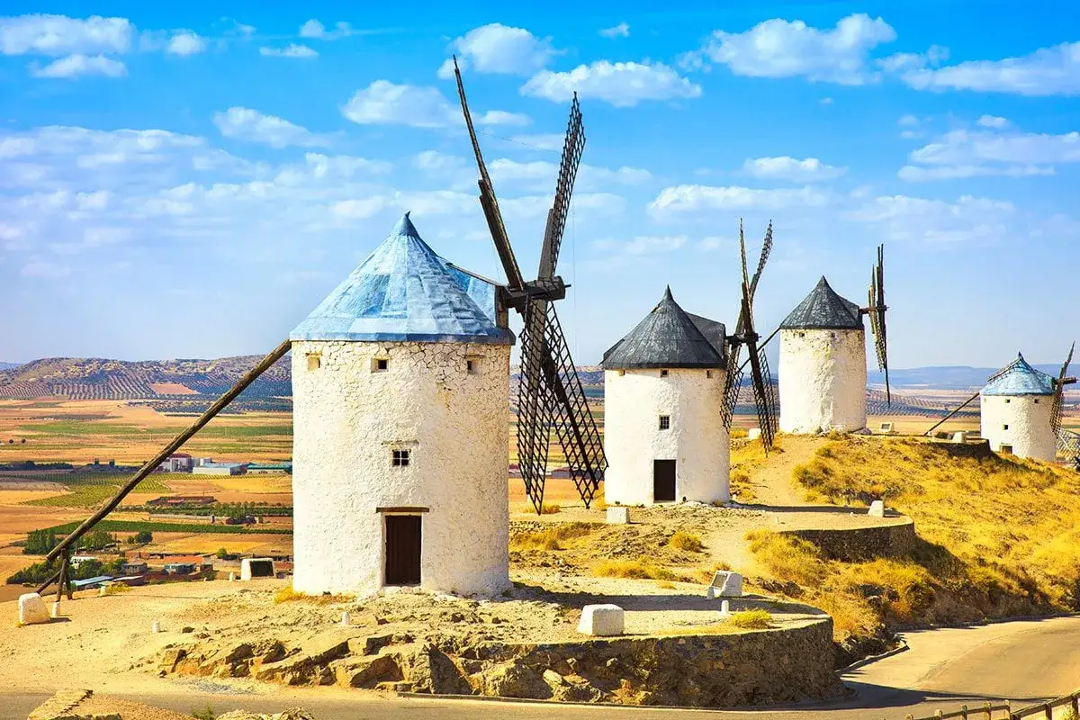 Wiatraki w Ciudad Real na tle błękitnego nieba i pól.