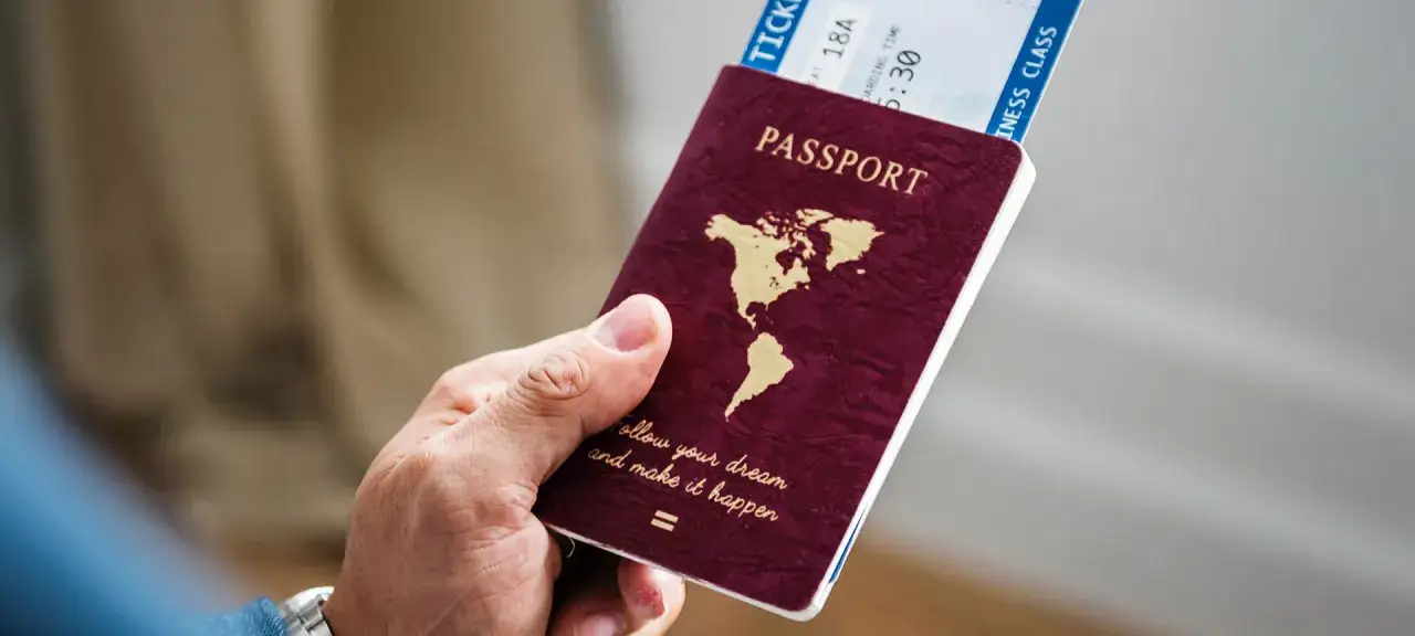 Dłoń trzyma paszport i bilet lotniczy. Czy do Hiszpanii trzeba paszport? Tak, jeśli podróżujesz spoza strefy Schengen.