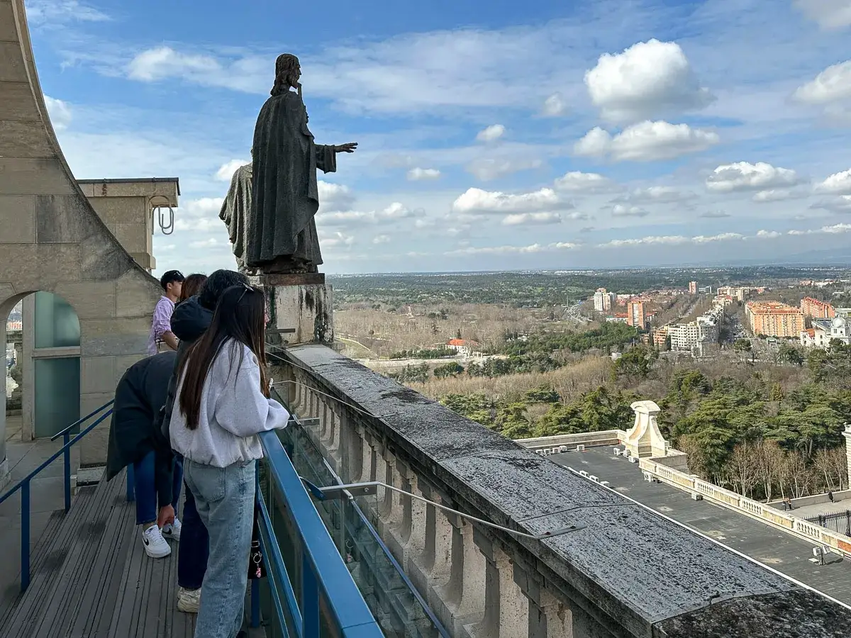 Widok na madryt centrum z tarasu z pomnikiem Chrystusa. Grupa turystów podziwia panoramę miasta.