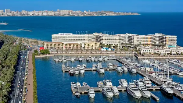 Alicante wczasy: luksusowe jachty w marinie, hotel Meliá Alicante i plaża z palmami.